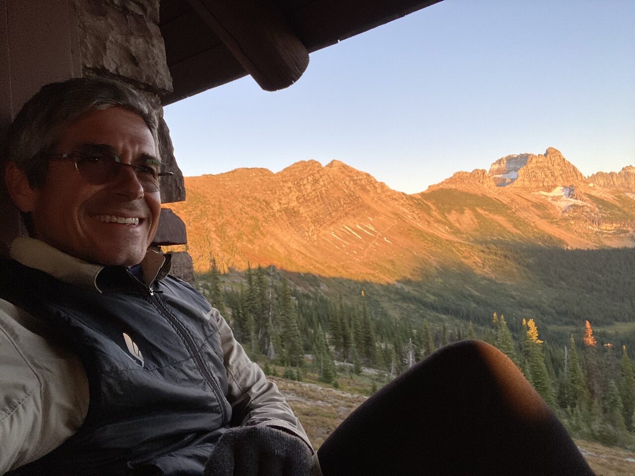 Mountains through chalet window, with jeff noel sitting on window ledge