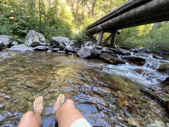 hiker's bare feet soaking in cold stream