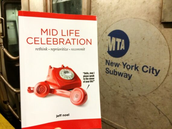 The book Mid Life Celebration Book in the New York City subway