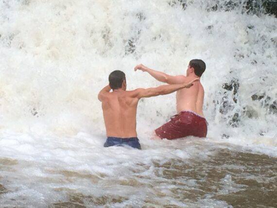 Two shirtless guys at a waterfall