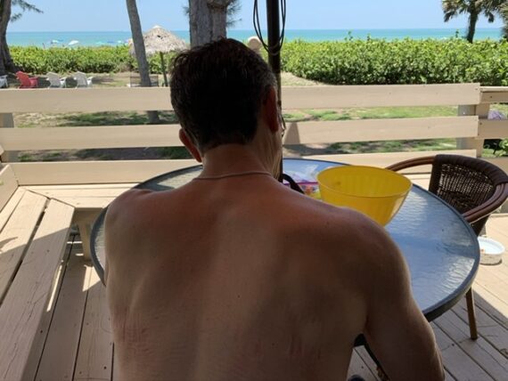 man with back to camera sitting at beach