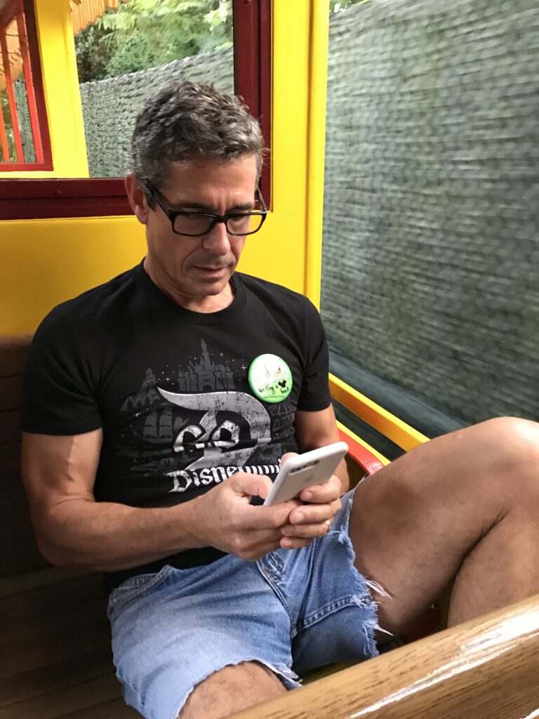 Disney author Jeff Noel writing on iPhone on Disney train