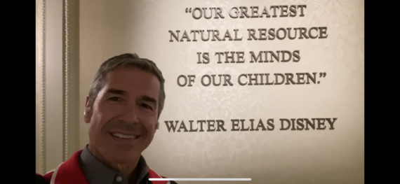 Disney Speaker Jeff noel in front of framed Walt Disney Quote