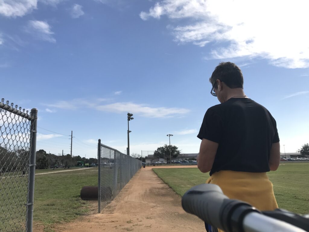 man standing at edge of softball field