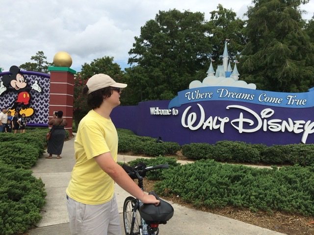 teen with bike at Walt Disney World entrance sign