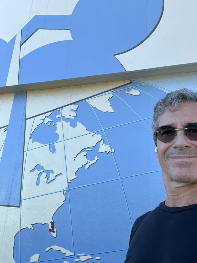 man standing by blue wall with map