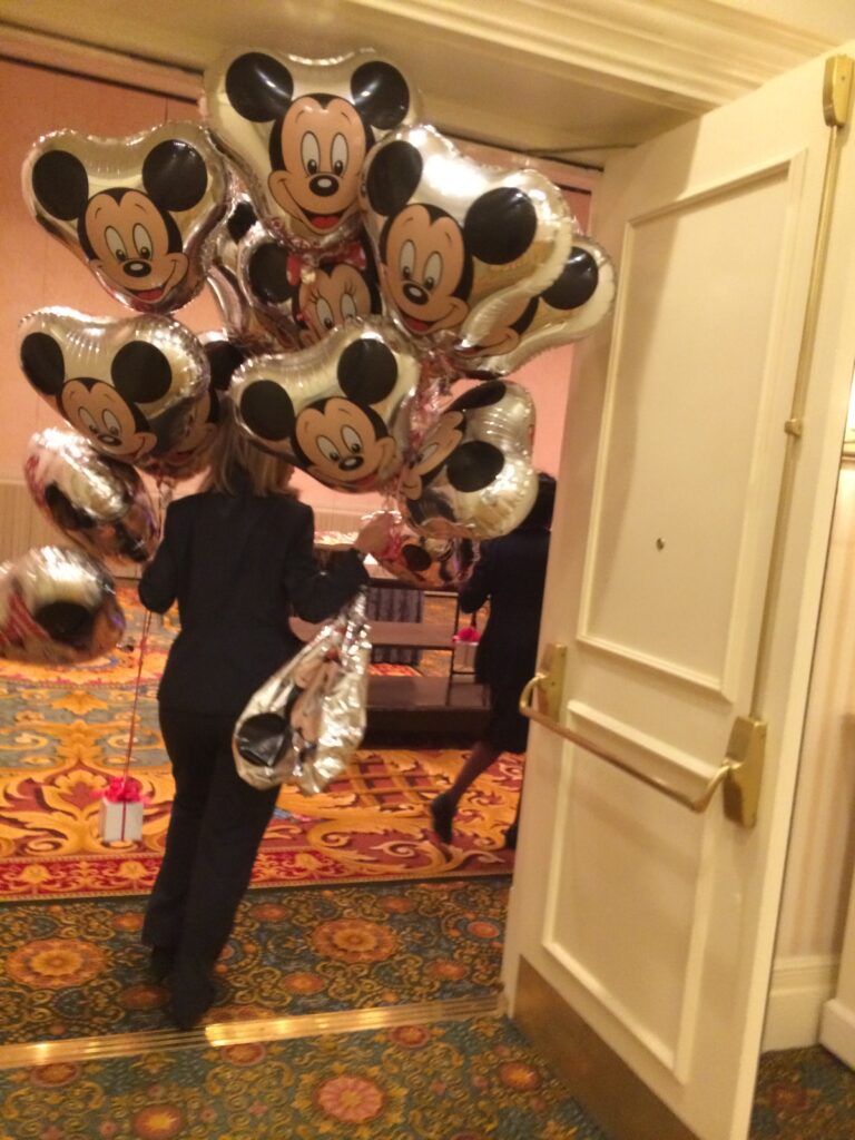 person carrying a dozen Mickey Mouse balloons