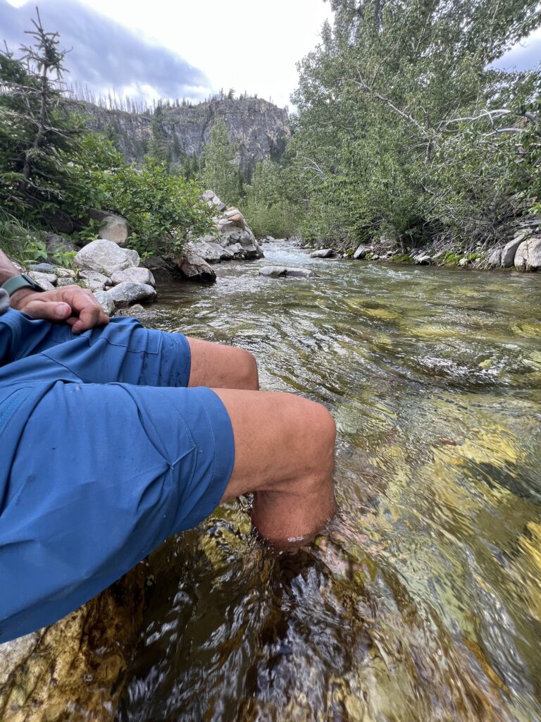 Person sitting with legs in a creek