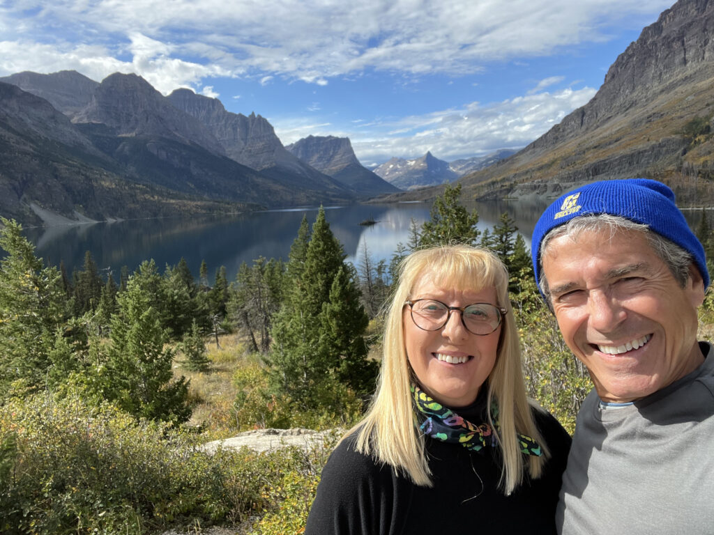 a couple posing by a mountain lake