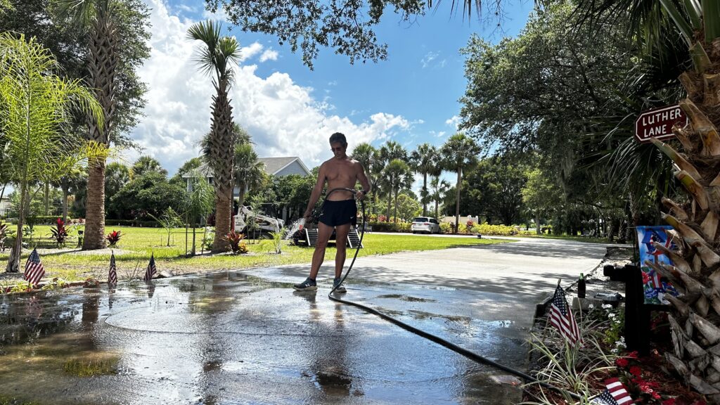 Man hosing off driveway