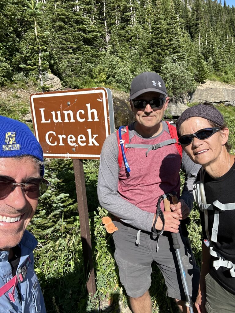 three hikers in front of trailhead sign