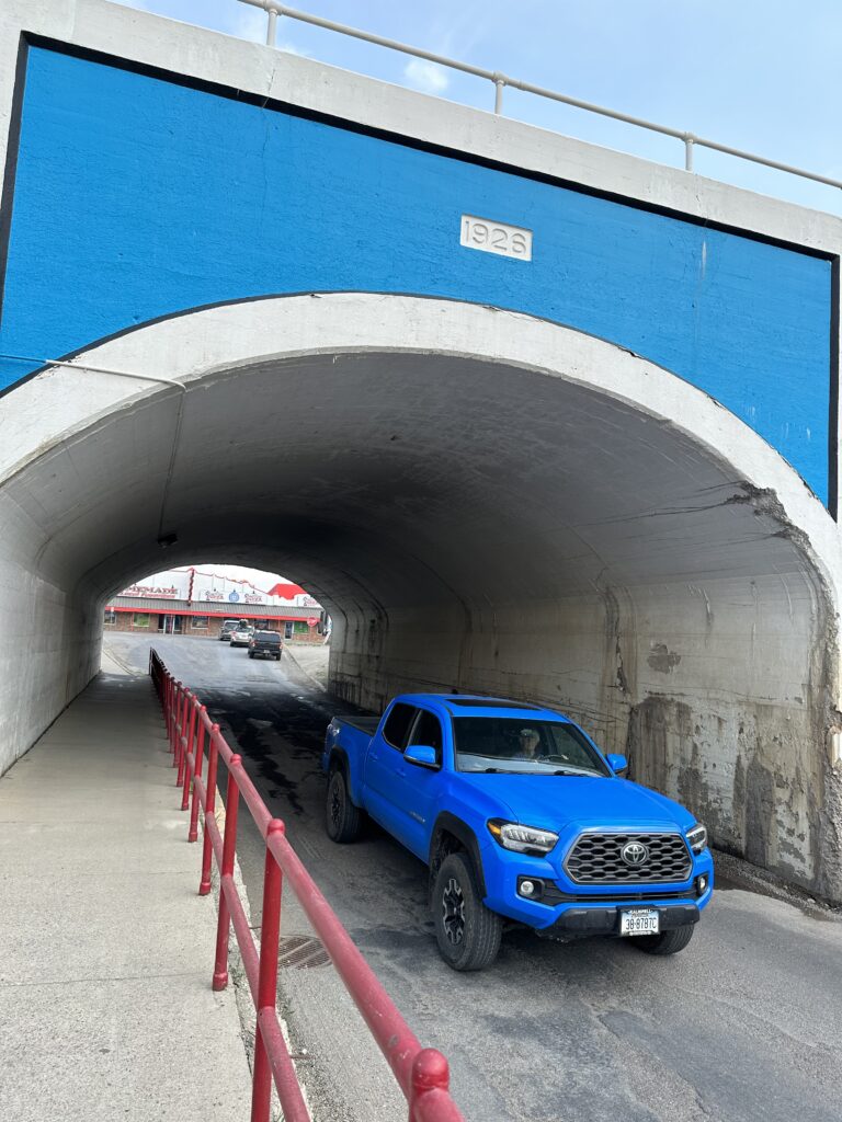 Blue truck under blue overpass