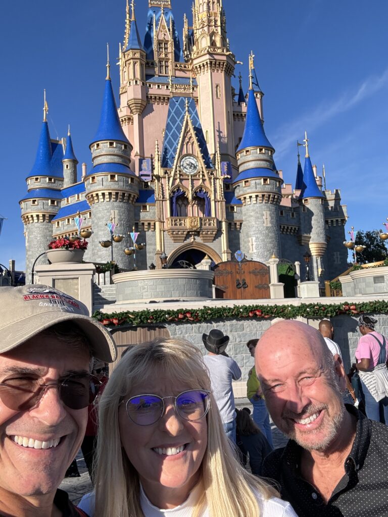 Three adults in front of a Disney castle