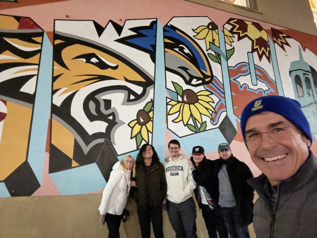 Six people posing next to building wall art