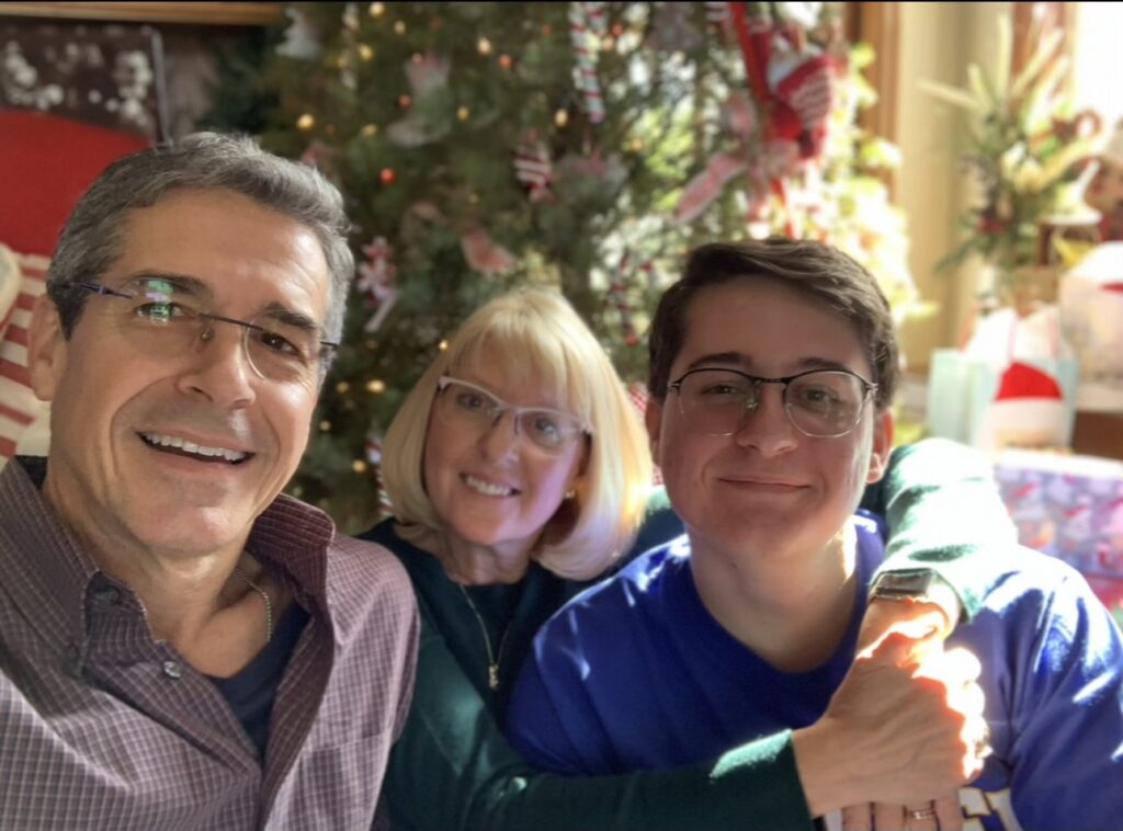 Family of three next to Christmas tree 