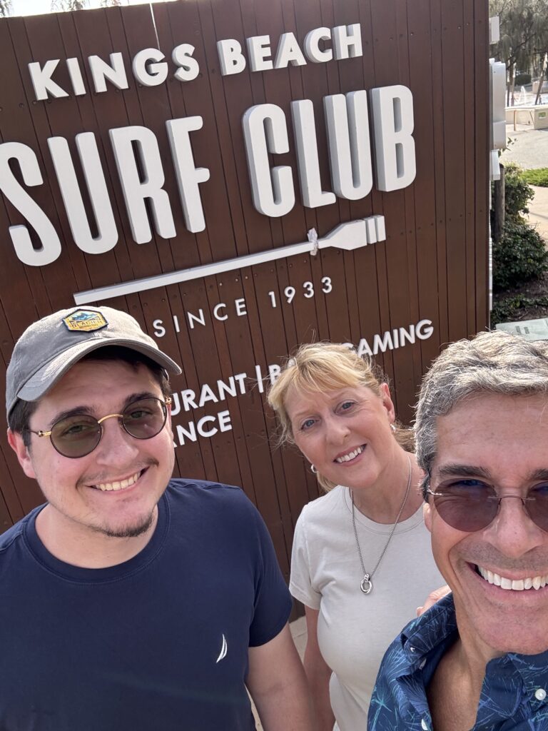 Three people in front of restaurant sign