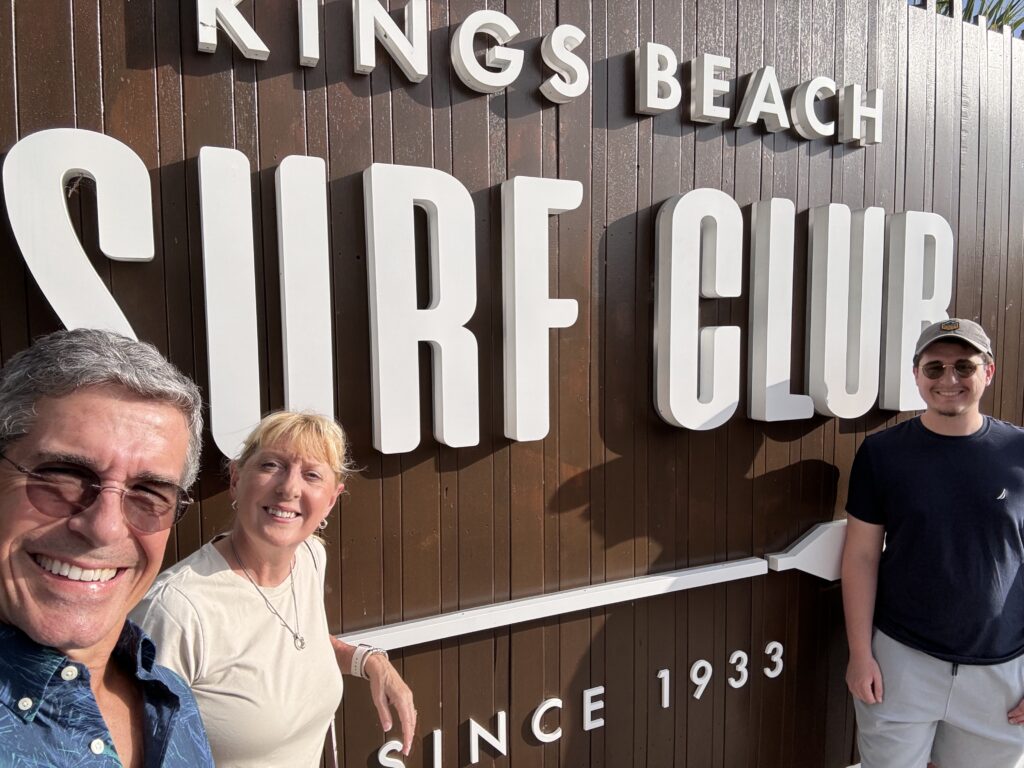 Three people in front of restaurant sign