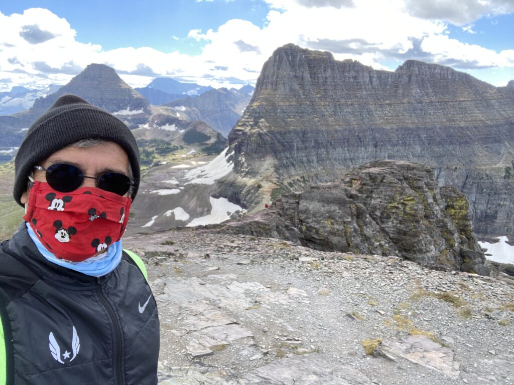man wearing covid mask on a mountain in Glacier National Park